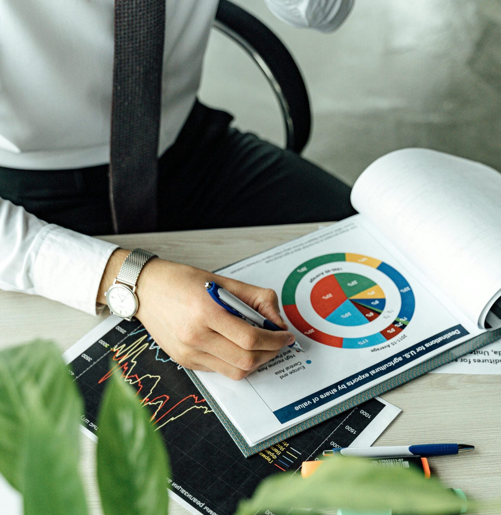Business professional analyzing financial graphs and charts at an office desk with a laptop.